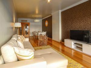 ein Wohnzimmer mit einem weißen Sofa und einem TV in der Unterkunft Balcony with view, private garage, an elevator in Setúbal