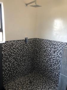 a bathroom with a black and white tiled wall at Villa 134 Modipane in Gaborone