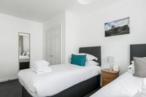 twee bedden in een kamer met witte muren bij Just Beachy in Poole