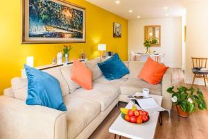 a living room with a white couch with blue and orange pillows at Luxury City Apartment Underground Parking 5* in Belfast