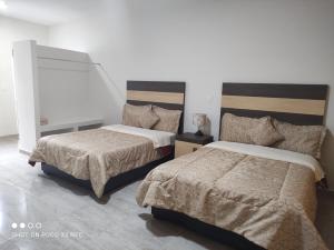 a bedroom with two beds and a white wall at Hotel del Bosque in Torreón