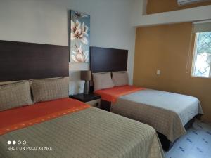 um quarto de hotel com duas camas e uma janela em Hotel del Bosque em Torreón