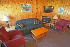 ein Wohnzimmer mit einem Sofa, Stühlen und einem TV in der Unterkunft Colonial Bay Motel and Cottages in Huntsville