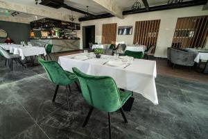 ein Esszimmer mit weißen Tischen und grünen Stühlen in der Unterkunft Hotel GardeNN in Belgrad