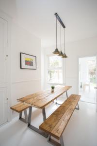 uma sala de jantar com uma mesa de madeira e banco em Elegant York House - on a beach road, sleeps 12, with sea views em Worthing