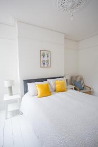 um quarto branco com uma cama com 2 almofadas amarelas em Elegant York House - on a beach road, sleeps 12, with sea views em Worthing