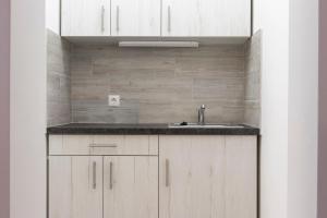 a kitchen with white cabinets and a sink at Airport Wanderer Inn - Vándor fogadó in Vecsés