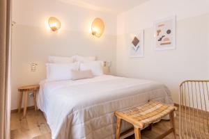 a bedroom with a large white bed and a chair at Hôtel Flor in Saint-Florent