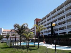 een groot appartementencomplex met een zwembad en palmbomen bij Casa del Sol in Manilva