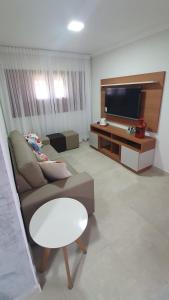 a living room with a couch and a flat screen tv at Condomínio Village , Casa Darci-Pé na Areia in Maragogi