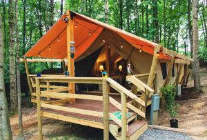 a tent with an orange roof in the woods at Country Road Cabins in Hico