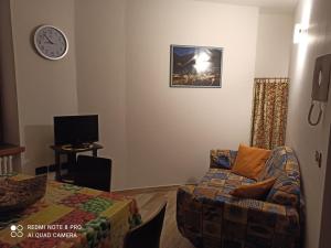 uma sala de estar com um sofá e um relógio na parede em La casa di Nonna Lia em Dimaro
