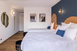 two beds in a hotel room with white and blue at Hôtel Flor in Saint-Florent