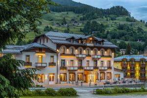 ein großes Gebäude mit einem Berg im Hintergrund in der Unterkunft Hotel Pejo in Peio Fonti