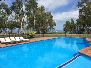 a swimming pool with two lounge chairs next to a fence at Arcadia Village Motel in Arcadia