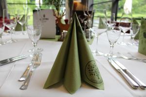 a table with green napkins on a table with glasses at Hotel Rennsteig in Masserberg
