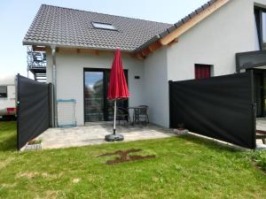 a red umbrella in the yard of a house at Zettler`s Ferienwohnung in Aichstetten