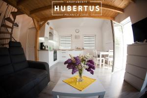 una sala de estar con un jarrón de flores sobre una mesa en Hubertus, en Polanica-Zdrój