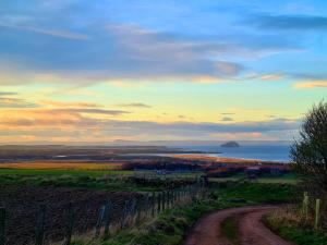 a dirt road in a field with the ocean at Eco Indigo in Dunbar