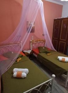 two beds in a room with pink and green at Sofia Margarita's Rooms in Agios Gordios