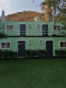 a green building with two doors and a grass yard at H CASE in San Juan Cosalá
