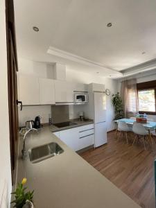 a kitchen with white cabinets and white appliances at Apartamentos Cantarería, Jazmín. in Setenil