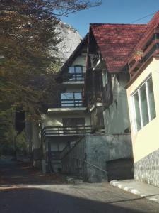 ein Haus mit rotem Dach und einem Gebäude in der Unterkunft Apartament Kalinderu K3 Busteni in Buşteni