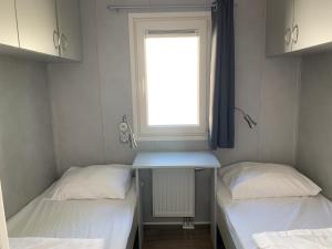 twee bedden in een kleine kamer met een raam bij Doelweg 35 Chalet 172 - No Companies in Goedereede
