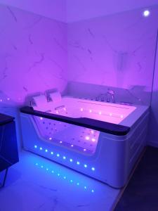 La salle de bains blanche est pourvue d'une baignoire avec un éclairage violet. dans l'établissement Suite Miro Charme et volupté, à Perpignan