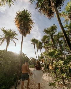 una pareja caminando por la playa con palmeras en Playa Esperanza Tulum, en Tulum