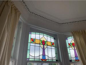 Grangemouth Apartments في فالكيرك: نافذة زجاجية ملطخة في غرفة مع أعمدة