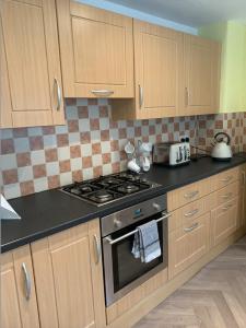 a kitchen with wooden cabinets and a stove top oven at Grangemouth Apartments in Falkirk