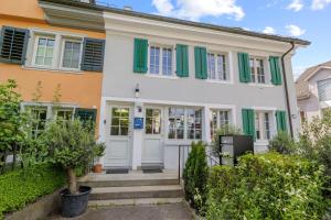 una casa con persianas verdes y una puerta blanca en GUEST HOUSE HERMES Contactless Self Checkin, en Zúrich