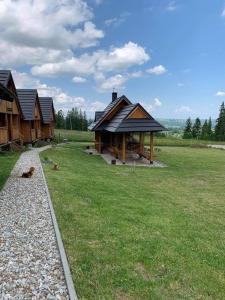 a group of wooden buildings in a field with grass at Domek na skarpce in Zakopane
