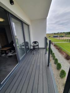 a wooden deck with a table on the side of a house at Apartamenty u Aleksandry in Ustronie Morskie