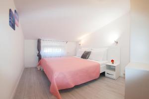 a white bedroom with a pink bed and a window at Apartments SoMi in Poreč