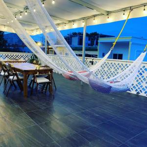a hammock on a balcony with a table and chairs at Hosteleria Casa Margarita in Mazatlán