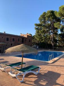 una silla y una sombrilla junto a la piscina en Masia de San Juan - castillo con piscina en plena Sierra Calderona, en Segorbe