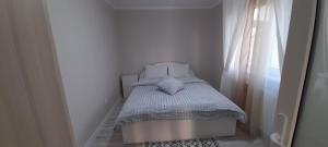 a small bed in a white room with a window at Casă de vacanță in Izvoare