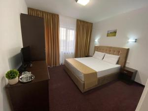 a hotel room with a bed and a television at Prestige House in Tulcea