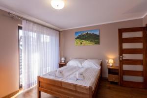 ein Schlafzimmer mit einem Bett und einem großen Fenster in der Unterkunft Apartamenty u Słodyczki in Mizerna