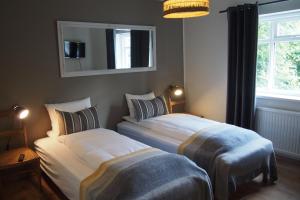 2 camas en un dormitorio con espejo y ventana en Granastaðir Guesthouse, en Granastaðir