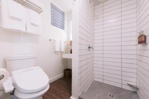 a white bathroom with a toilet and a shower at SCP Hilo Hotel in Hilo