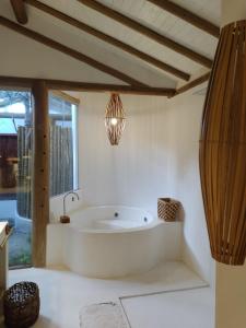ein Bad mit einer großen Badewanne und einem Fenster in der Unterkunft Casa Nuhatê Trancoso - Praia do Espelho in Praia do Espelho