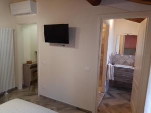Zimmer mit einem TV an der Wand und einem Spiegel in der Unterkunft Il Vicolo in Lucca