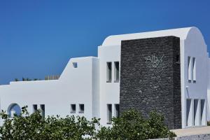 a white building with a clock on the side of it at Alleys All-Suite Hotel & Spa in Pirgos