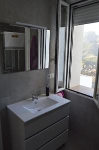 a bathroom with a white sink and a window at CASA CARAVINA in Benimantell