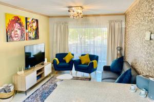 a living room with blue chairs and a television at Phoenix Rising Apartment in Midrand