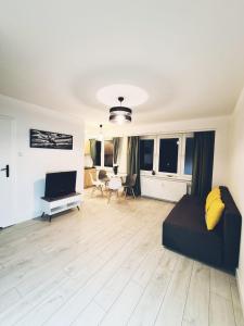 a living room with a couch and a television at Apartament Parkowy Mrągowo in Mrągowo