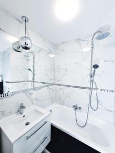 a white bathroom with a shower and a sink at Apartament Parkowy Mrągowo in Mrągowo
